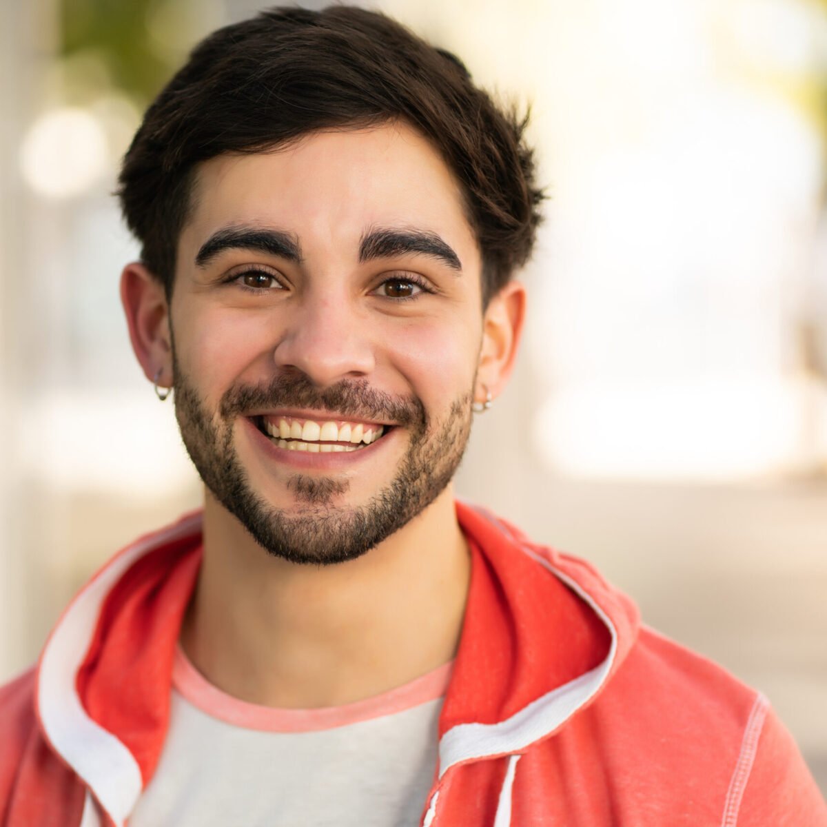 Close-up of young man smiling while standing outdoors at the street. Urban and lifestyle concept.