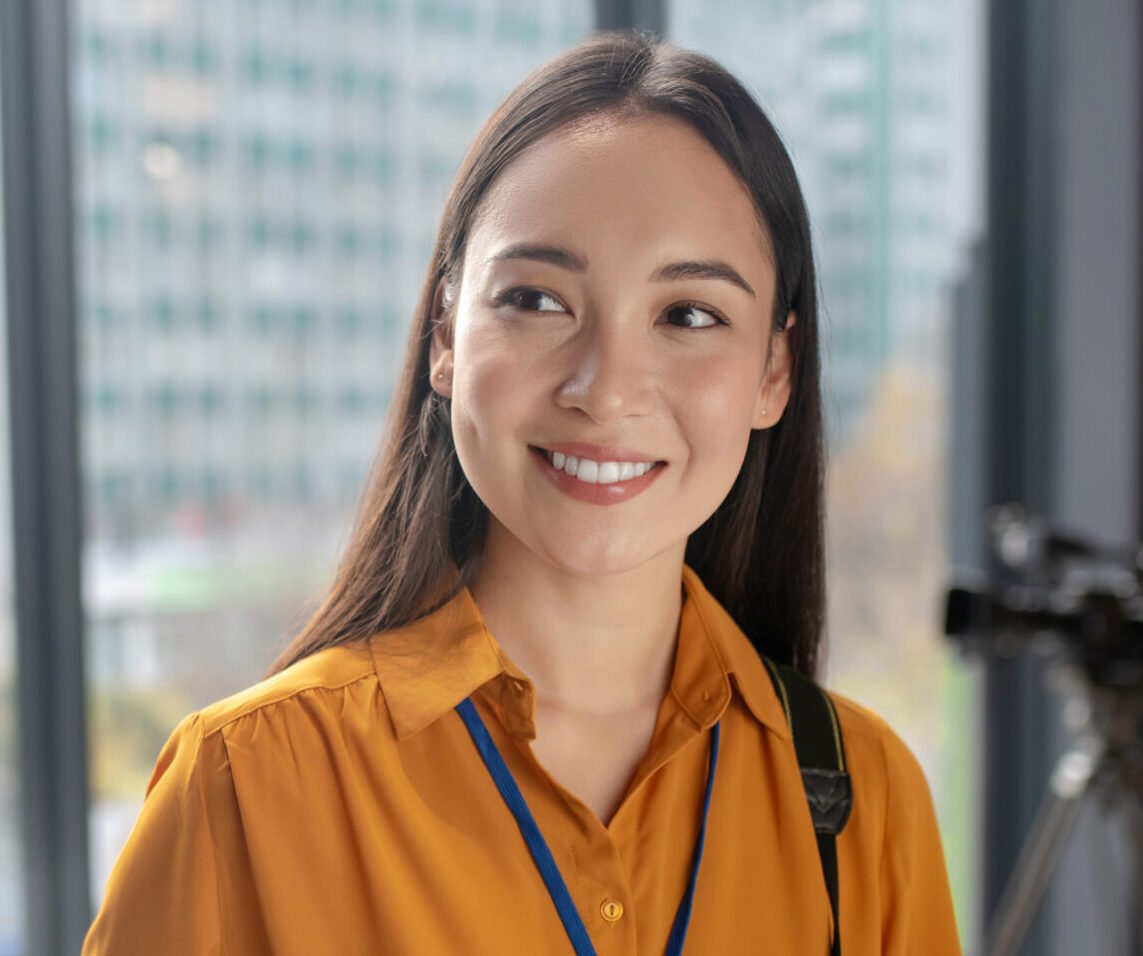 During working day. Dark-haired young cute reporter holding a camera smiling nicely
